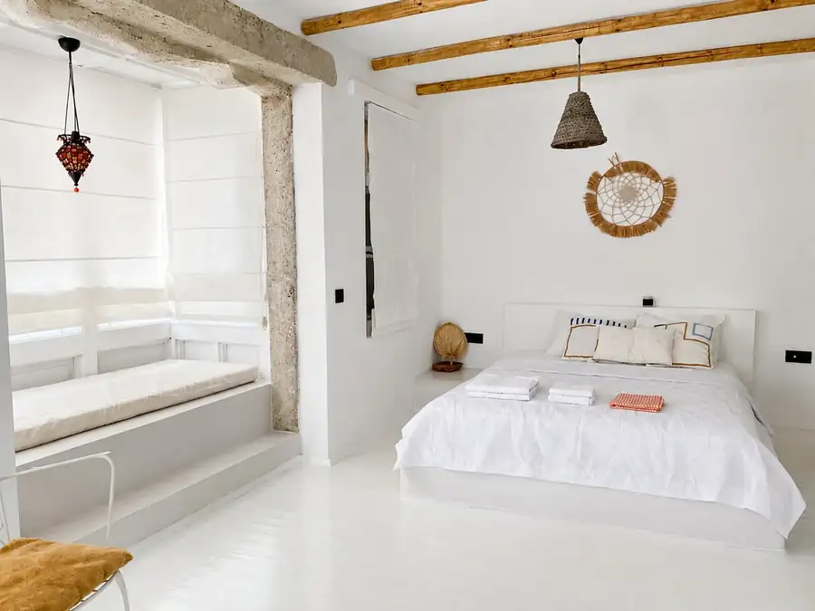 Beyaz yataklı ve pencere oturmalı oda